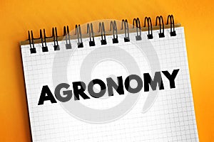 Agronomy is the science and technology of producing and using plants by agriculture, text concept on notepad