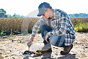 Agronomy specialist measuring soil pH value using soil tester outdoors