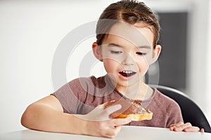 Ah yeah My favourite. a little girl looking excitedly at a piece of toast with chocolate spread on it.