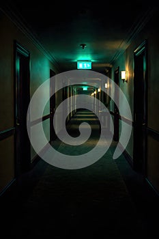Dark Empty Hotel Corridor With Emergency Exit Sign Creating Suspense And Isolation Mood