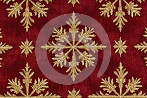 Elegant red and gold snowflake pattern on a textured fabric background creating a luxurious holiday theme perfect for seasonal photo
