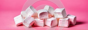 a pile of white marshmallows on a pink surface