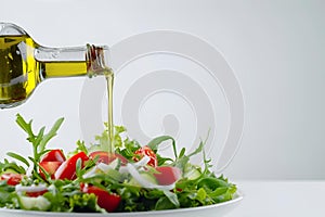 a person pouring olive into a bowl filled with fresh salad