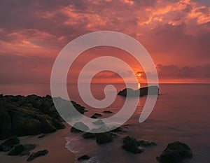 AI generated illustration of a vibrant sunset over rocky ocean shoreline with serene waters