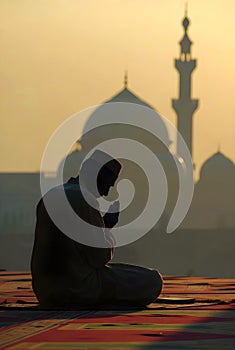 Silhouette Of A Man Praying At Sunset With Mosque And Minaret Background