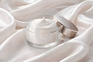 Open Luxury Face Cream Jar Displayed On Flowing Silk Fabric