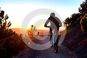 Cyclist Riding Mountain Trail Overlooking Glowing Sunset Horizon