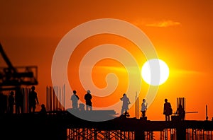 AI-generated silhouettes of construction site workers in the sunset