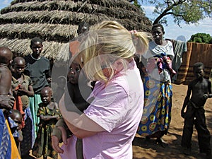 Aid relief worker holding starving hungry African baby in village Africa