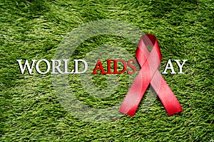 Aids Awareness Sign Red Ribbon, the fight against AIDS sign on green grass