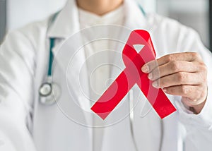 Aids red ribbon in doctorÃ¢â¬â¢s hand for World aids dayand HIV virus awareness concept photo