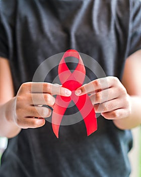 Aids red ribbon on girl teenagerâ€™s hand support for World aids day and national HIV/AIDS awareness month campaign concept