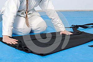 An aikidoka girl folding her hakama for Aikido training