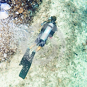 Air bubbles emerging from diver at coral reef under water