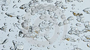 Air bubbles rising water surface closeup. Bubbling mineral liquid in light