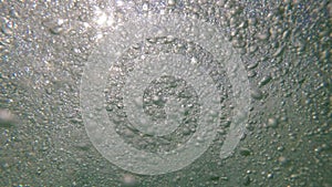 Air bubbles and sun rays on the sea surface. Air bubbles in the water