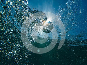 Air bubbles at water surface in sea in clear blue water