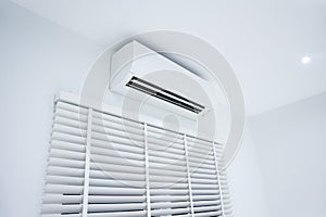 Air conditioner and blinds in white room.