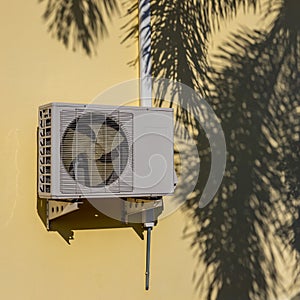 Air conditioner compressor near palm leaf shadow