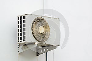 Air conditioner compressor unit on white wall.