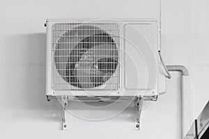 Air conditioner compressor unit on white wall.