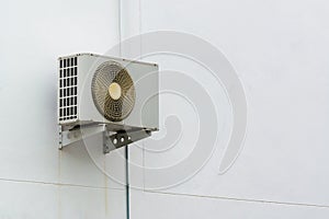 Air conditioner compressor unit on white wall.