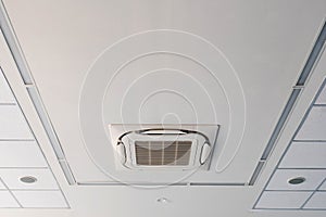 The air conditioner is installed on the ceiling in the white room with the lamps. Air conditioning is installed on the ceiling whi