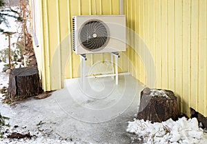 Air conditioner machine outdoors on rack on domestic home house yellow wall.