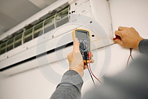 Air conditioner, maintenance hands and voltage meter with construction, wall and technician man. AC repair, professional