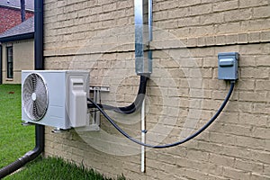 Air Conditioner mini split system next to home with brick wall
