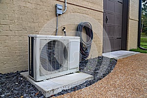 Air Conditioner mini split system next to home with brick wall photo