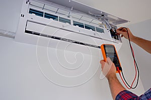 Air conditioner repair and maintenance. The engineer diagnoses the electrical part of the indoor unit of the air conditioner with