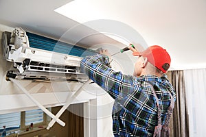 Air conditioner service. Worker at climatization system installation indoors