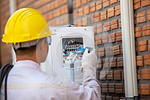 The air conditioner technician checks the electrical power of the air conditioner compressor from the outside