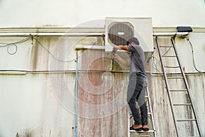 Air conditioner technician is installing the air conditioner on the wall of the house