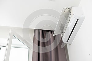 Air conditioner on top of white wall turned on, cooling down room interior during heat wave