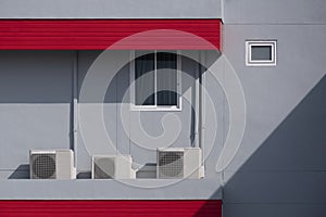 Air conditioning compressors with pipelines and glass window outside of gray building wall