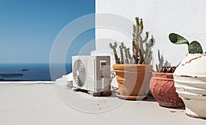 Air conditioning or heat pump unit near potted plants in Santorini, Greece.