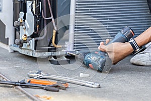 Air Conditioning Repair, technician man hands using a screwdriver fixing modern air conditioning system