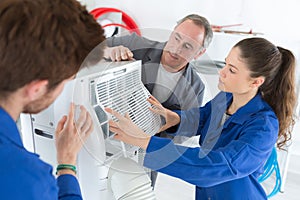 Air conditioning repairmen discussing problem with compressor unit