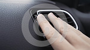 Air deflector and climate control inside a car. Action. Close up of car interior details with a hand touching deflector