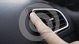 Air deflector and climate control inside a car. Action. Close up of car interior details with a hand touching deflector