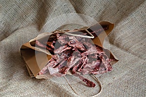 Air dried beef lungs in a paper bag on a mechina. Natural healthy treats for dogs and cats. Rustic style. Soft focus.