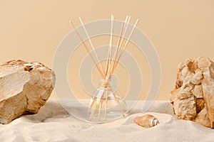 Air freshener on a natural background with sand, stones and shells. Perfume composition in a glass diffuser with reed sticks. Home