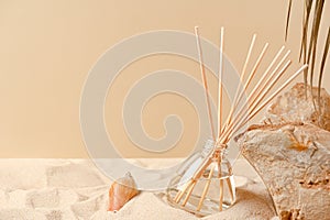 Air freshener on a natural background with sand, stones and shells. Perfume composition in a glass diffuser with reed sticks. Home