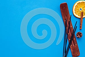 Air freshener sticks with cinnamon and orange on blue background top view mockup