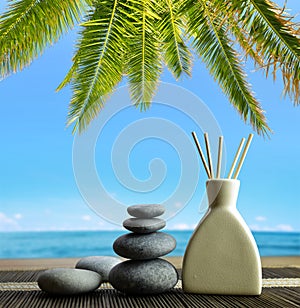 Air freshener with wooden aroma sticks and zen pebbles on the beach.