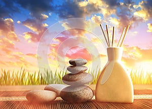 Air freshener with wooden aroma sticks and zen pebbles at sunset.