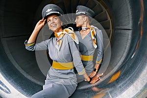 Air hostesses in pilot caps sitting in the turbofan engine photo