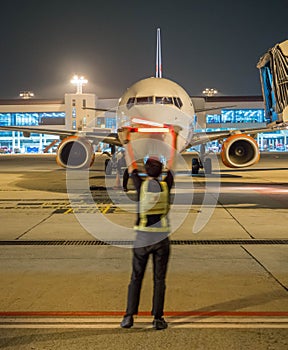 Air Marshaller in motion blur showing sign to tell captain to stop, night time